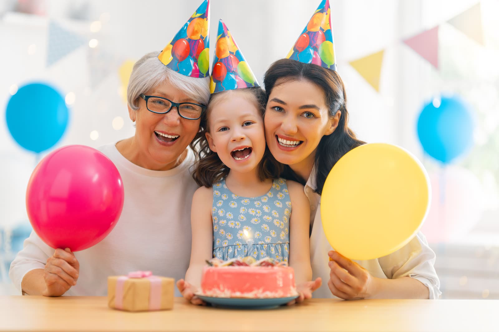 Grandmother, mother and daughter in party hats celebrating with a birthday cake